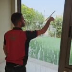 عامل ينظف زجاج نافذة ضمن أعمال التنظيف الشامل في العين