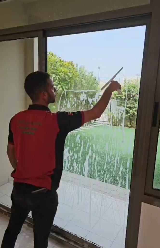 عامل ينظف زجاج نافذة ضمن أعمال التنظيف الشامل في العين